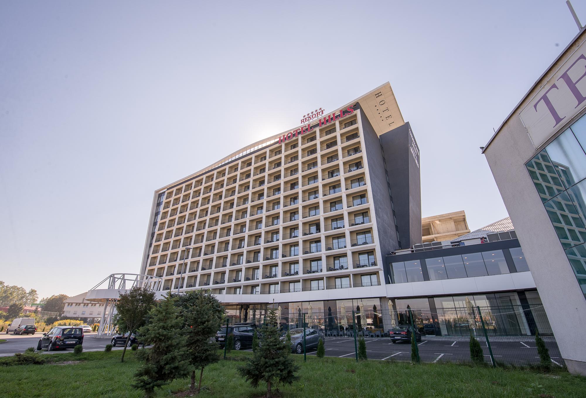 Hotel Hills Sarajevo Congress & Thermal Spa Resort Илиджа Экстерьер фото The photo shows a modern hotel building with multiple floors and a contemporary design. The structure features large windows arranged in a grid pattern and a prominent entrance area at the bottom. There are green areas, possibly with trees or landsca